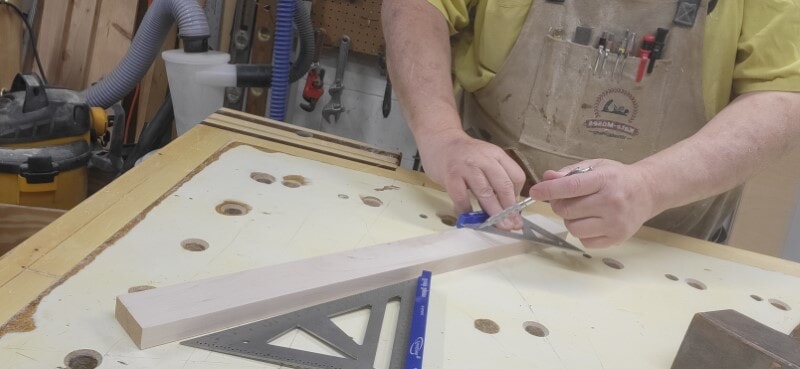 Marking a 45-degree layout line to meet a square cut Woodworker using a speed square to draw a 45-degree layout line connecting to a square cut line