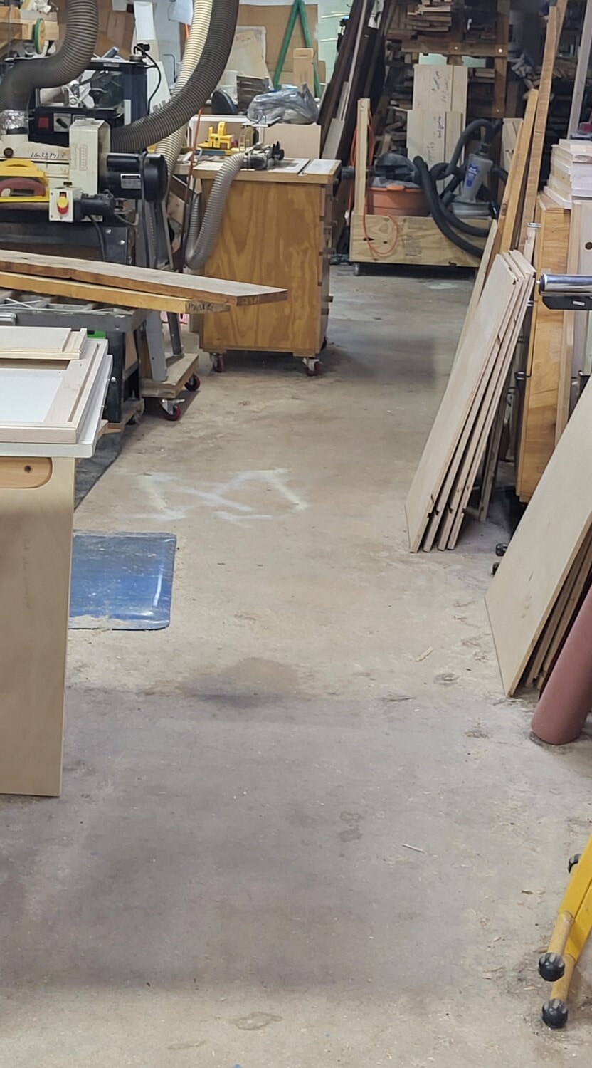 Clean woodshop floor with lumber and projects organized along the sides, leaving a clear walkway to reduce tripping hazards and improve safety