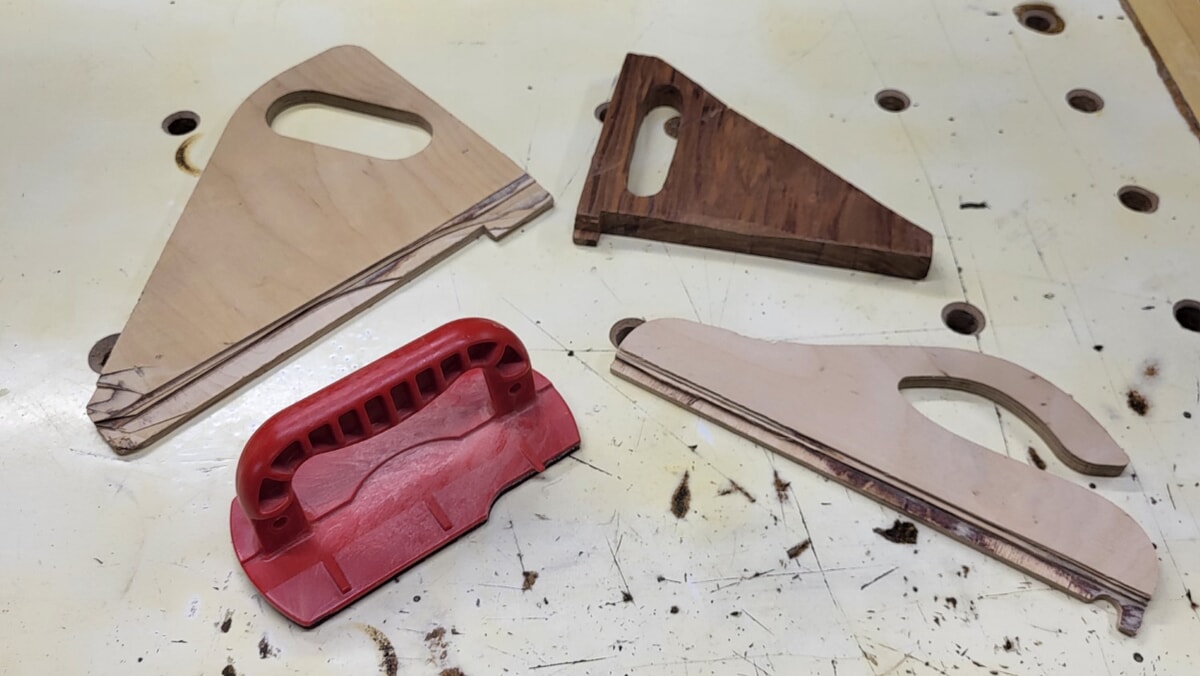 Damaged push shoes and push sticks on a workbench, showing cuts and wear from table saw and router table use, and kickback