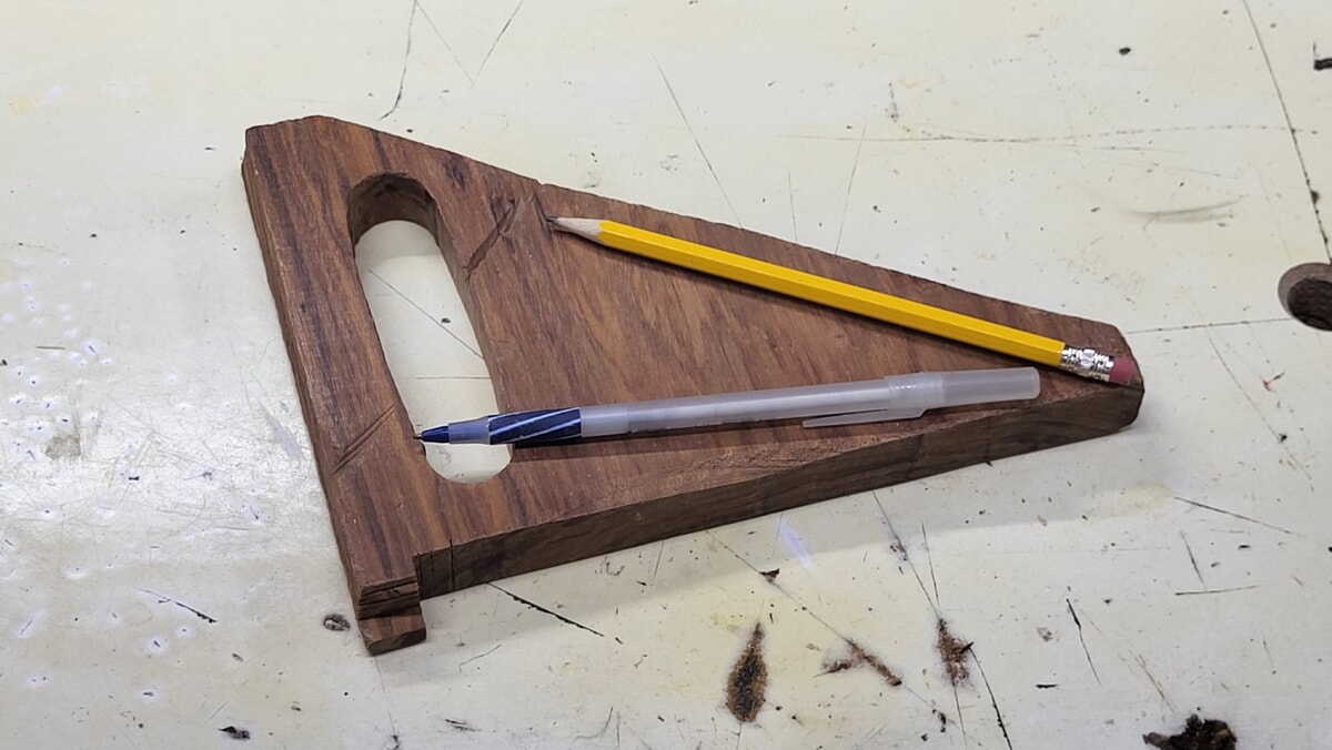 Wooden push shoe for table saw with visible cut marks from a kickback accident on the handle where the hand would have been