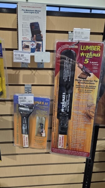 Lumber Wizard metal detector and moisture meters displayed on a Woodcraft wall rack.